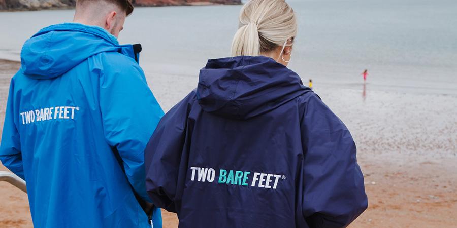 two people wearing two bare feet changing robes facing the sea