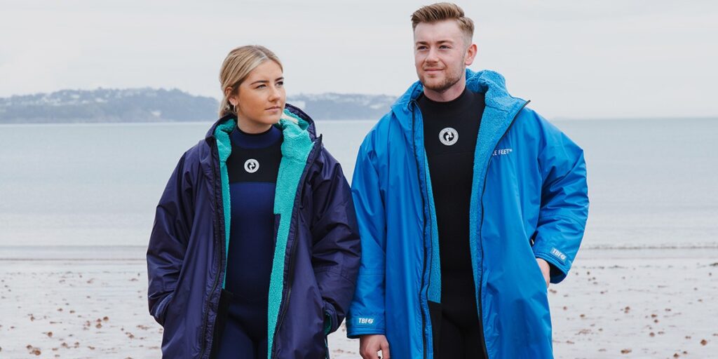 man and woman wearing changing robes by the sea