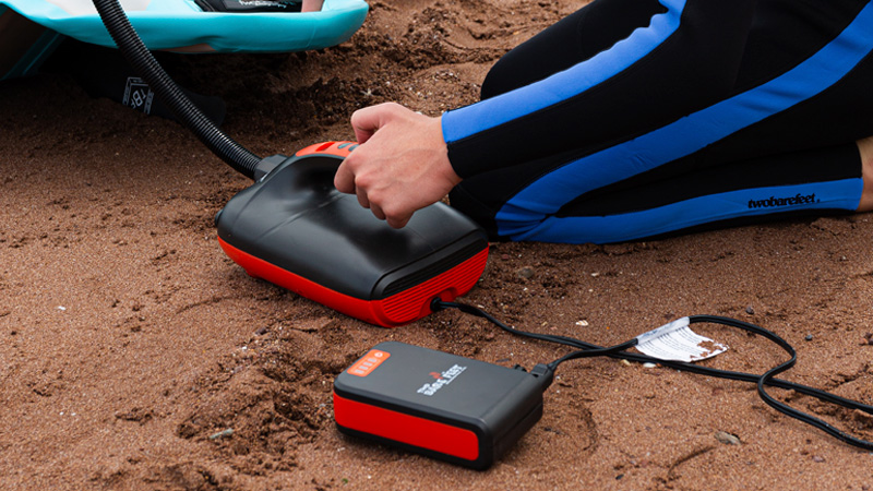 Close-up of a Two Bare Feet electric pump connected to a power bank on the beach