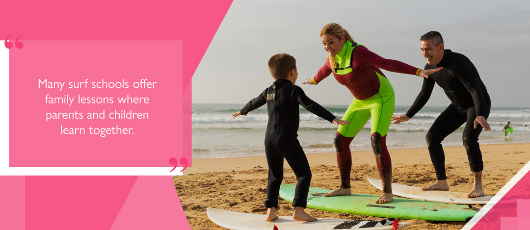 Family taking surf lessons together on the beach, practising balance on surfboards.