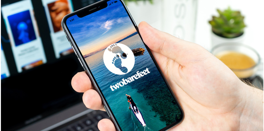 Phone displaying Two Bare Feet logo featuring paddleboarder on SUP in open water