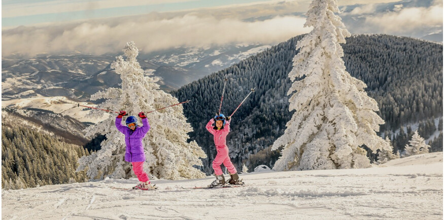 Two girls skiing on a mountain top
