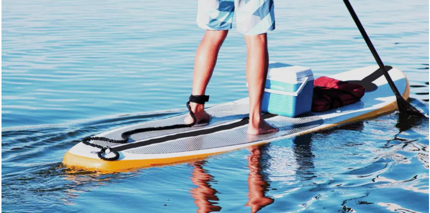 Paddleboarder standing on SUP while wearing ankle leash