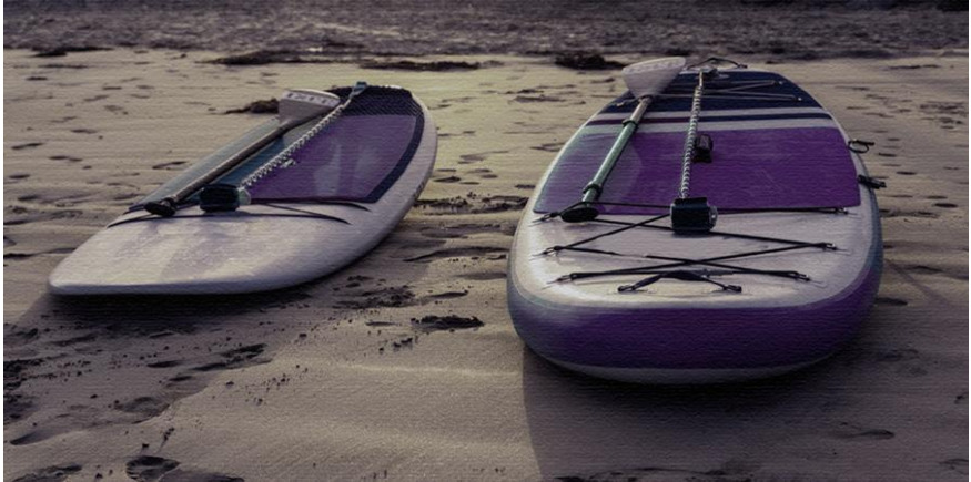 Inflatable SUP and hard board side by side on beach