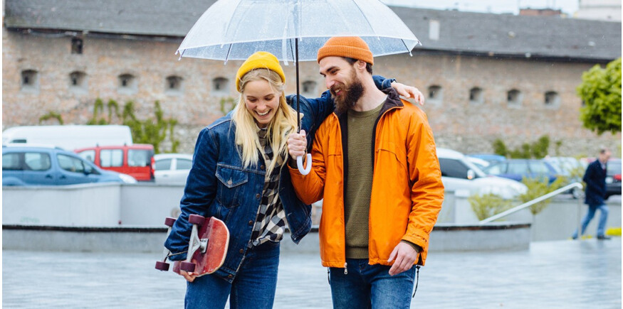 Skateboarding couple standing in the rain