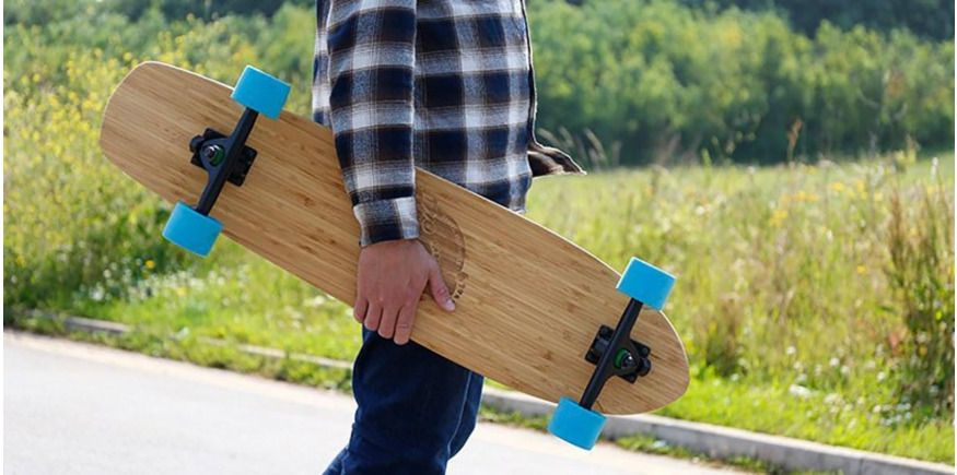 standing on the street with a bamboo longboard