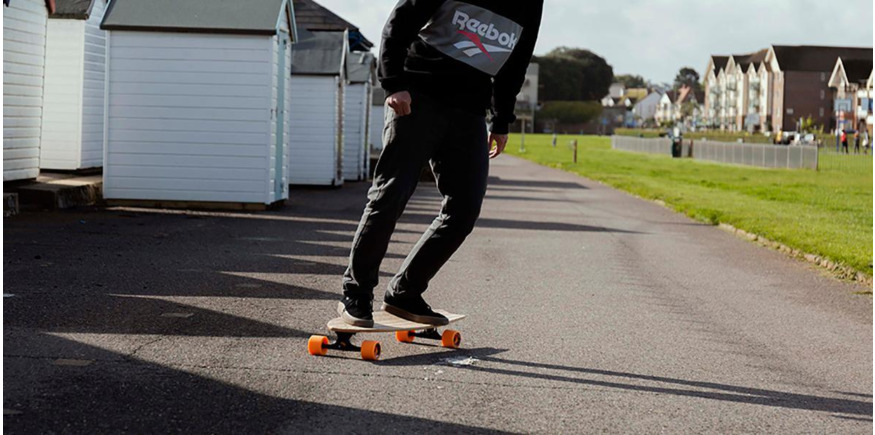 skater cruising on a longboard next to beach huts
