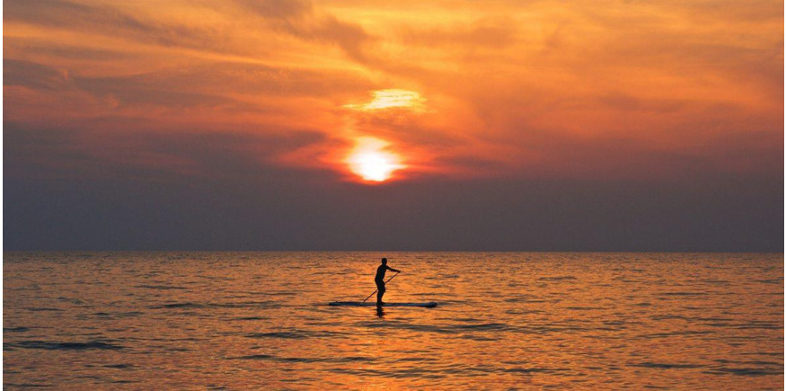man paddleboarding at sunset on the sea