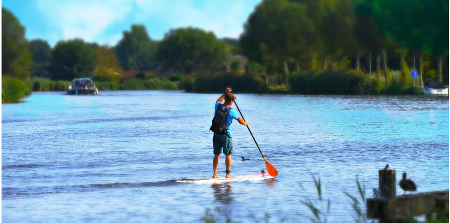 paddleboarder crossing a river on an inflatable sup