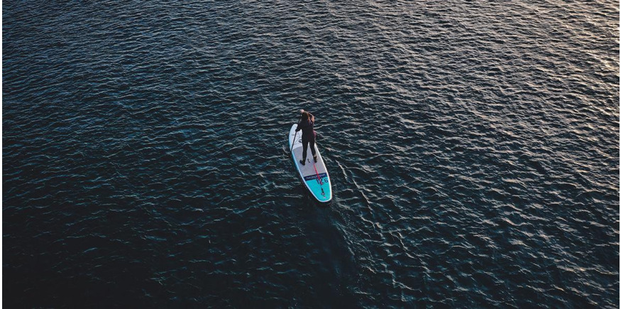 paddleboarding paddling a touring sup in the ocean photographed by a drone
