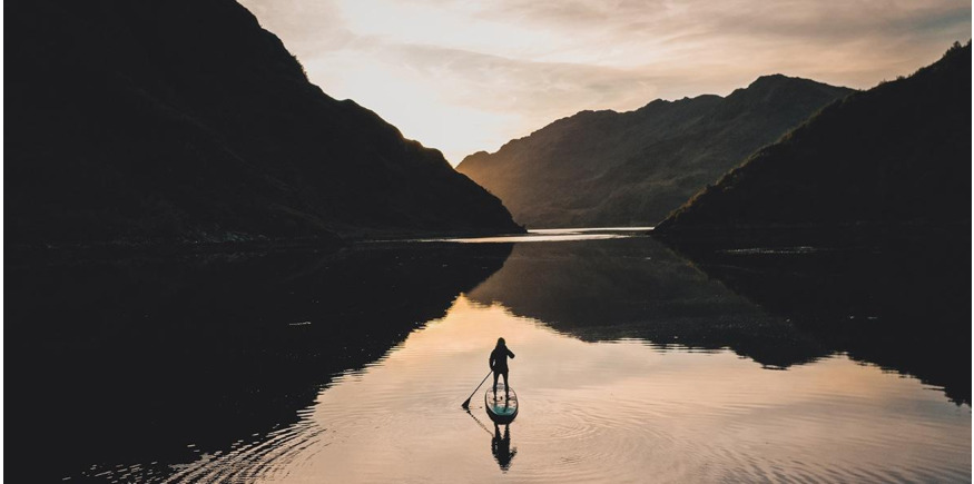 paddling into the sunset on a glassy Scottish loch lined by mountains