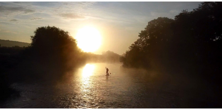 paddleboarding down the river at sunset