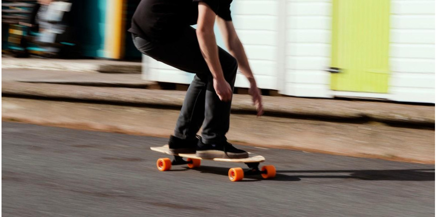 skater cruising on a longboard passed beach huts