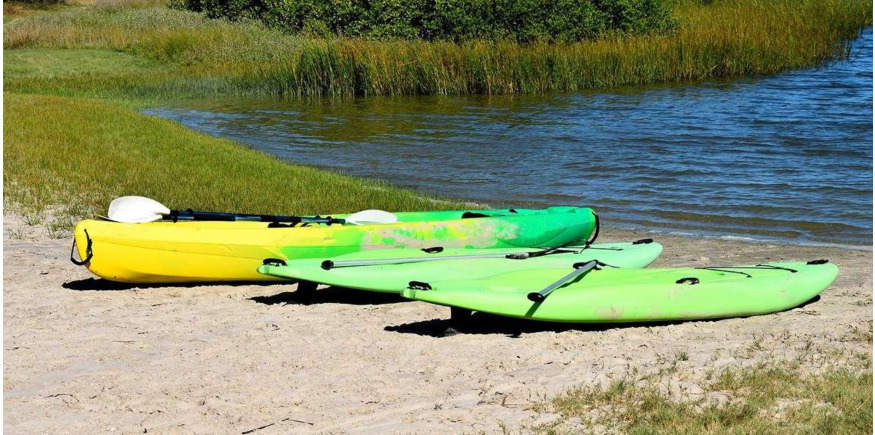 two sups and one kayak on the beach at a lake