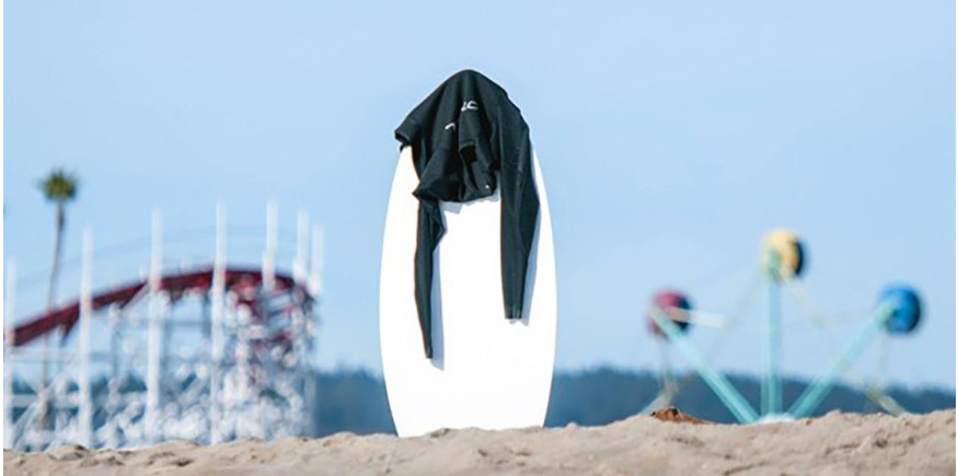 wetsuit hanging over skimboard on the beach