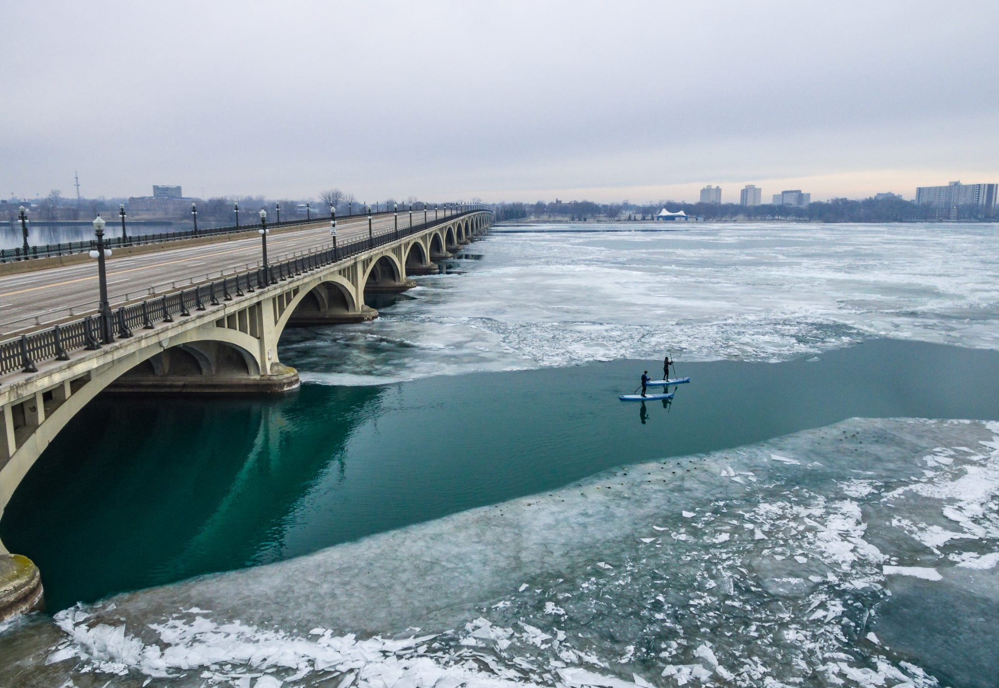 paddleboarders gliding down icy river
