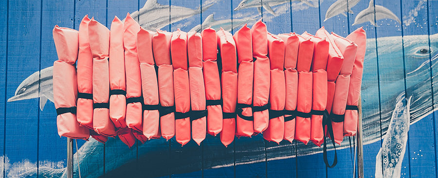a rack of buoyancy aids against a wall at a watersports centre