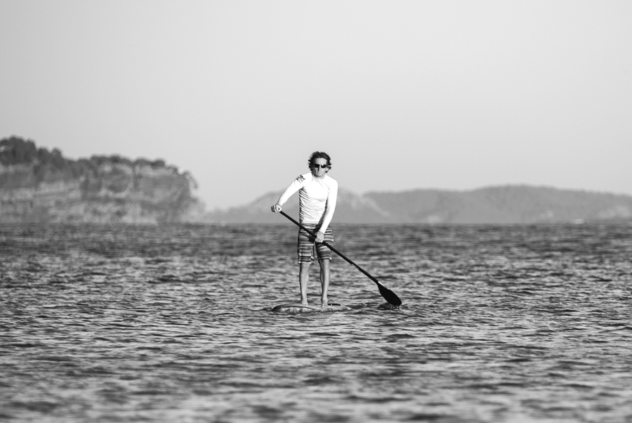 Clothed man paddleboarding in lake