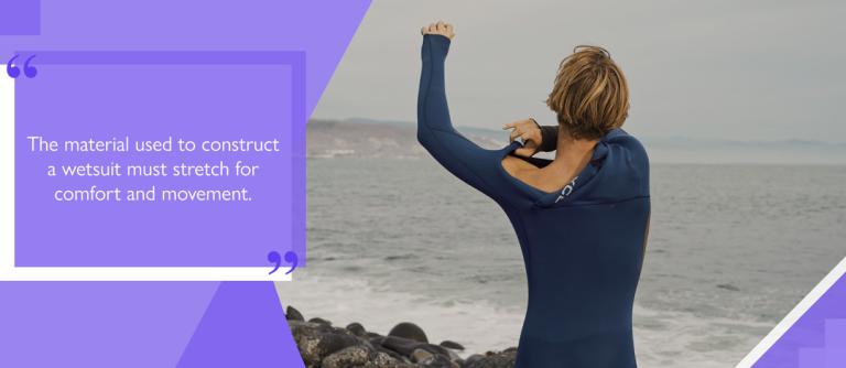 Surfer by the sea pulling on a neoprene wetsuit