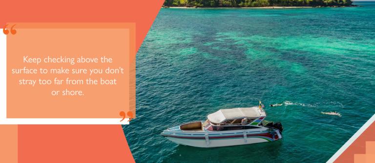 people snorkelling off a boat with text 'Keep checking above the surface to make sure you don't stray too far from the boat or shore'