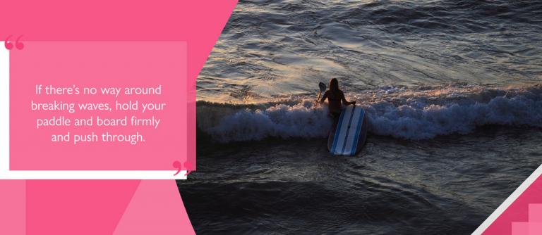 SUP surfer entering waves breaking on beach