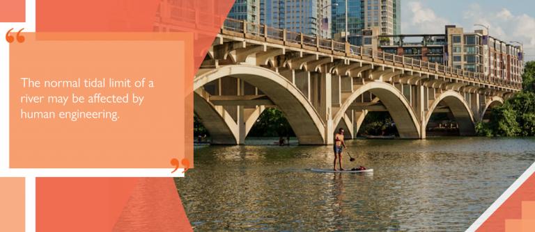 Paddler passing under bridge on SUP board