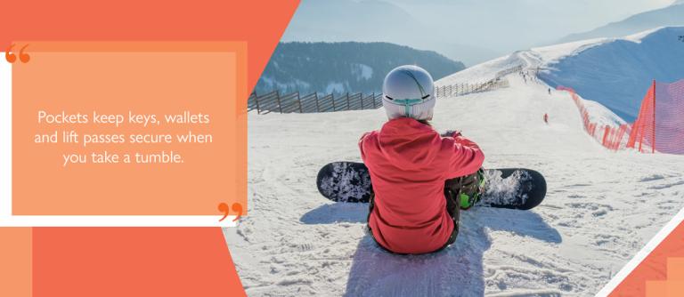 Snowboarder wearing ski jacket sat on snow at top of ski run