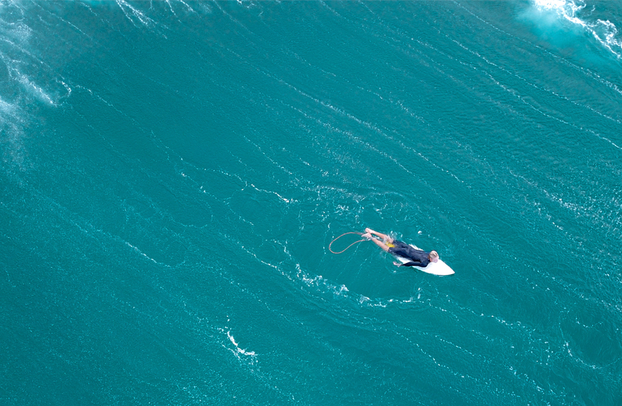 Paddle board rider wearing long-sleeved rash vest while lying on SUP