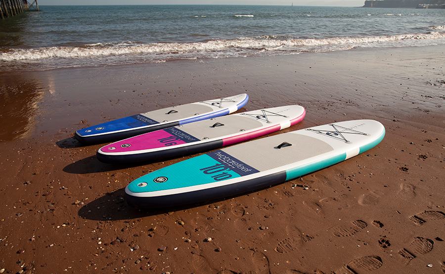 three different size inflatable paddleboards lined up on the sand next to the ocean