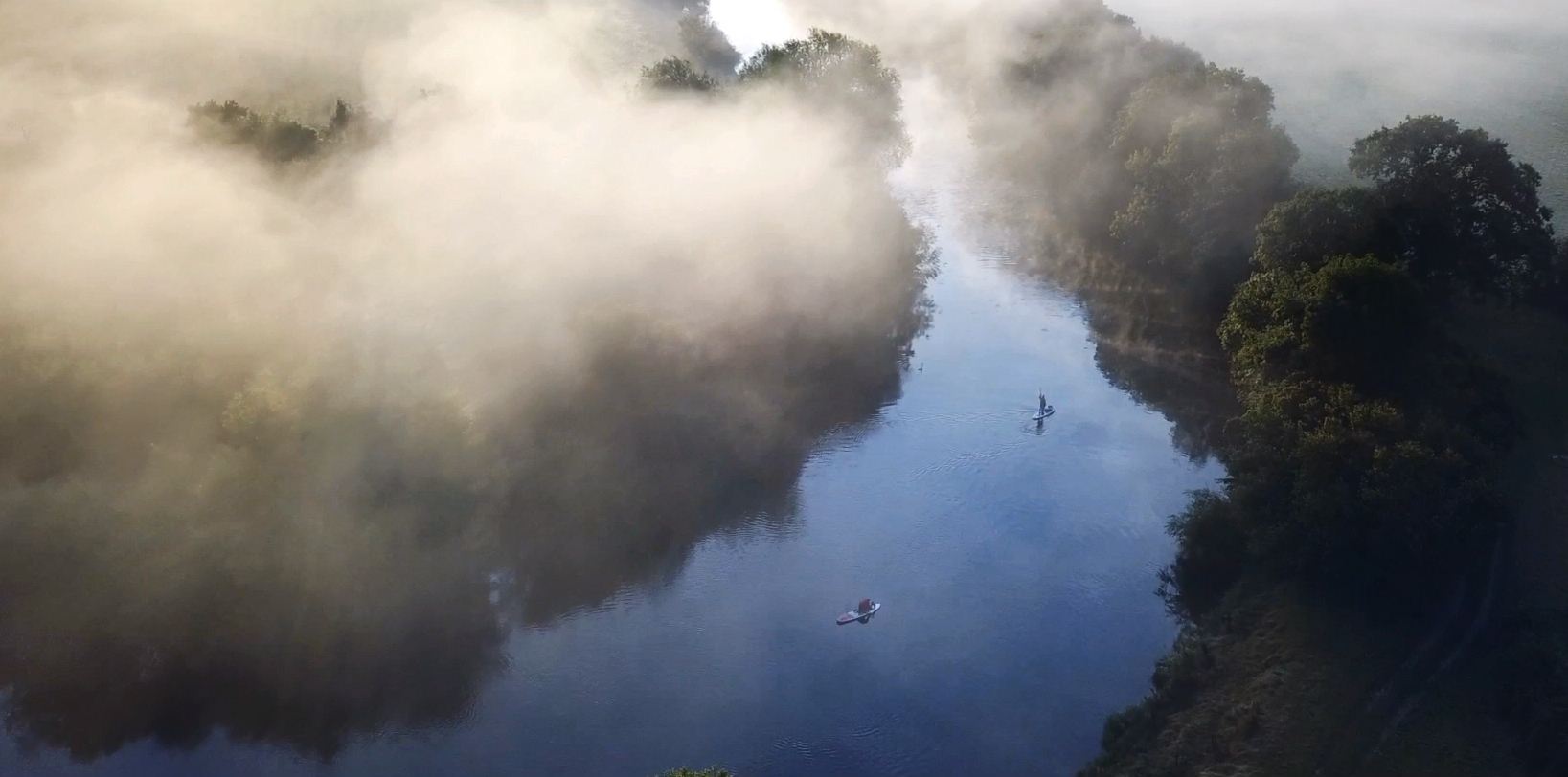 paddleboarding down the river on a misty morning 