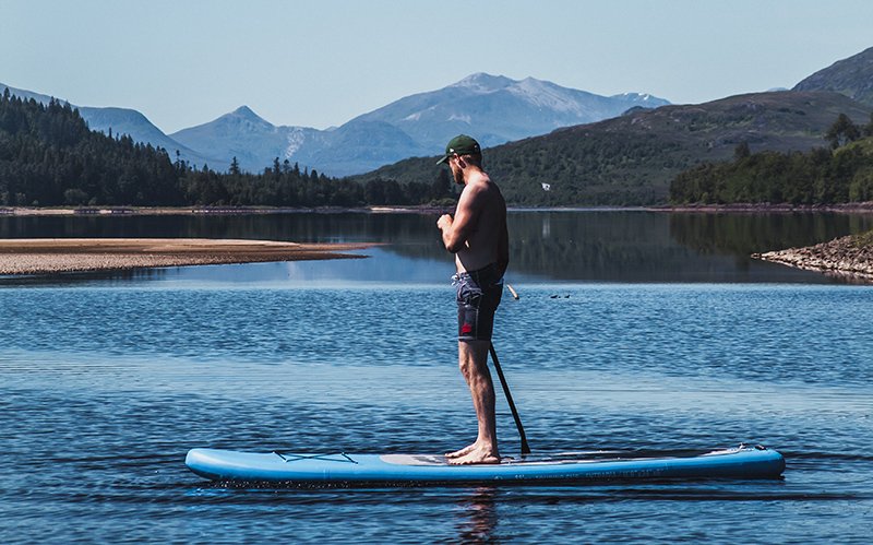 stand up paddleboarding with mountains in the background