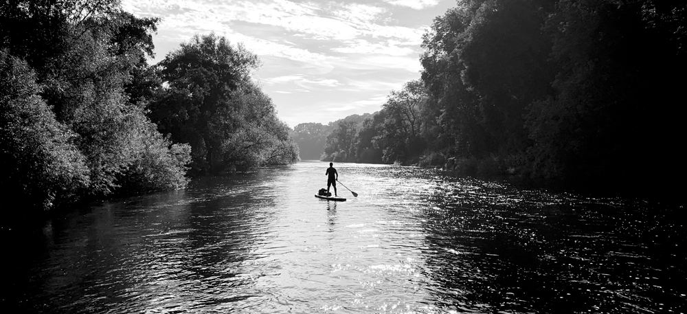 paddleboarder in black and white on calm water on the river wye