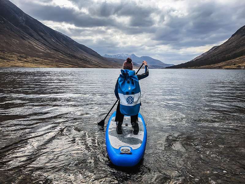 woman kneeling on a paddleboard on a Scottish lake